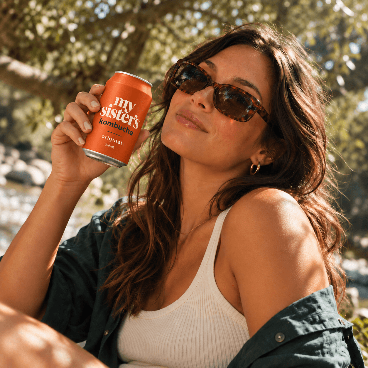 Person holding an Original kombucha can outdoors