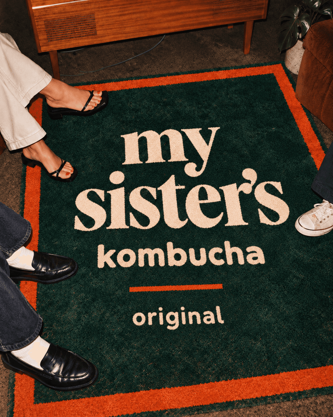 Forest rug with cream My Sister's Kombucha lettering and orange border
