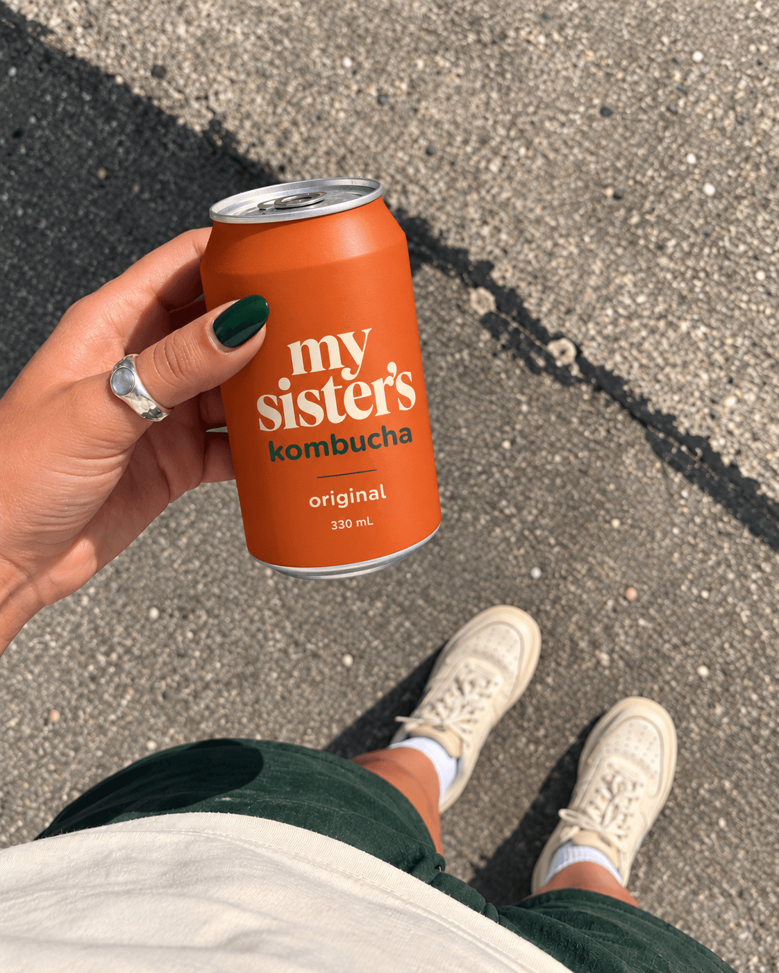 Hand holding a dry Original kombucha can in sunlight